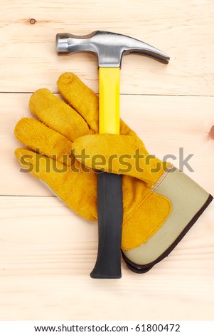 Hammer and worker glove over wood plank.  Tools