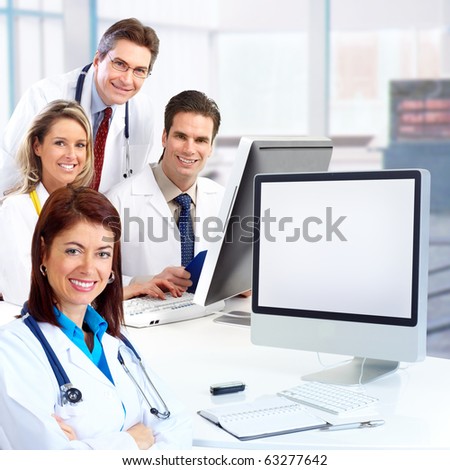 Smiling medical doctors with stethoscopes working with computer.