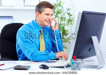Handsome smiling businessman calling by phone in the office