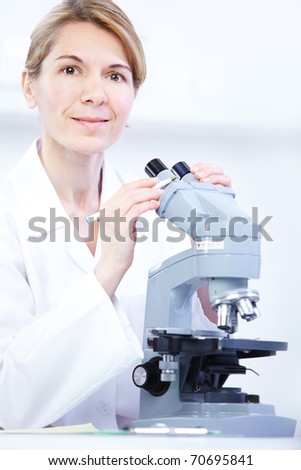 Woman working with a microscope in lab