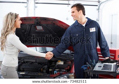 Handsome mechanic and client woman in auto repair shop.
