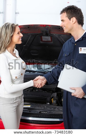 Handsome mechanic and client woman in auto repair shop.