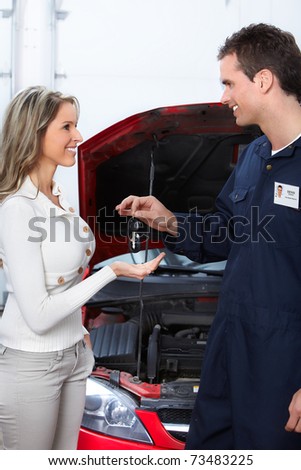 Handsome mechanic inspecting the tire pressure in auto repair shop.