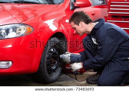 Mechanic changing wheel on car with impact wrench.