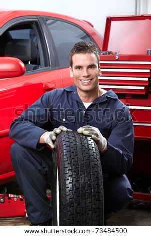 Handsome mechanic changing  wheels in auto shop.