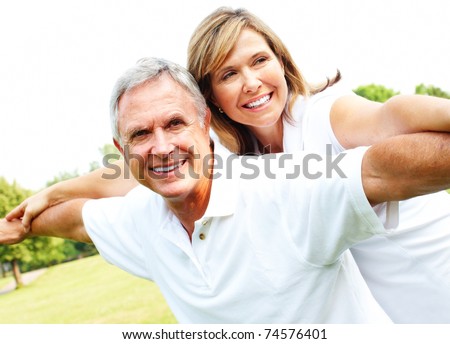 Happy smiling elderly seniors couple in park.