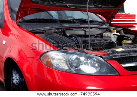 Car with open hood in auto repair shop.