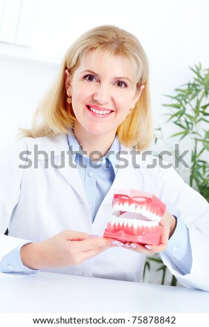 Smiling dentist with teeth anatomical model in the office