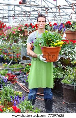 Young smiling florist working in the greenhouse.