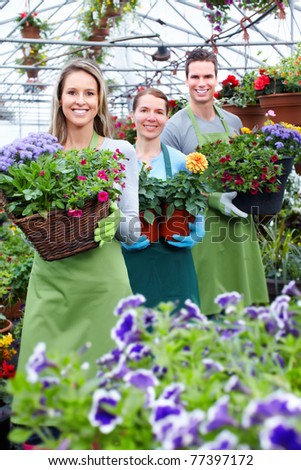 Young smiling people florists working in the greenhouse.