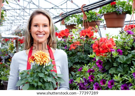 Young smiling woman florist working in the greenhouse.