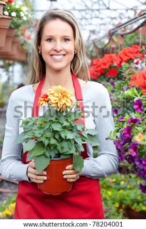 Young smiling woman florist working in the greenhouse.