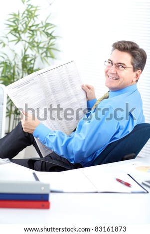 Mature business man reading newspaper in modern office.