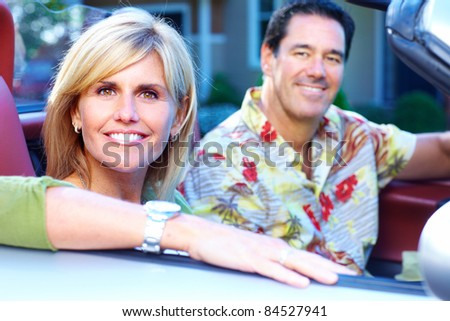 Happy smiling couple in a convertible car. People outdoors.