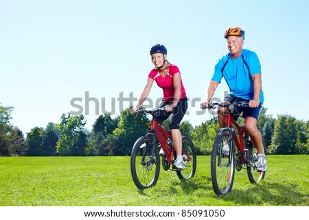 Happy senior couple  riding  in the park.