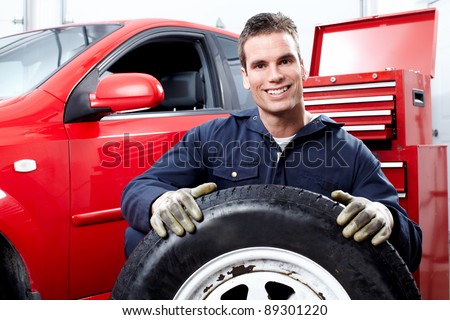 Professional auto mechanic changing a tire in auto repair shop. Garage.