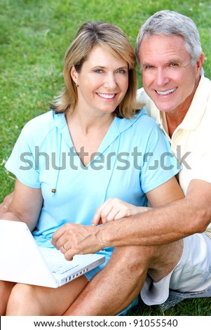 Happy senior couple in love in the park with laptop computer.