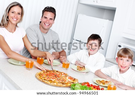 Happy family eating  pizza and vegetables at home.