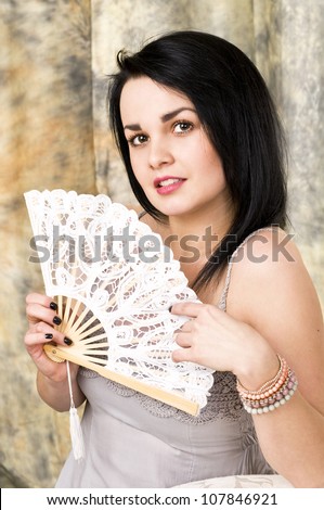 A beautiful woman with a fan . Portrait of an attractive young brunette .