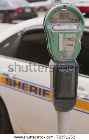 Traffic meter and Sheriff car next to road with cars in background
