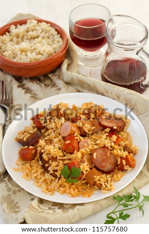 rice with chorizo and sausages on the plate and glass of wine
