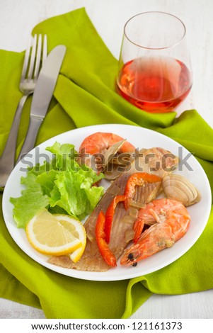 fish with seafood on the plate and glass of wine