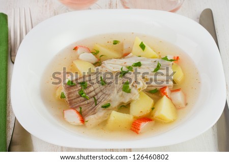 fish stew in the white plate with fork and knife