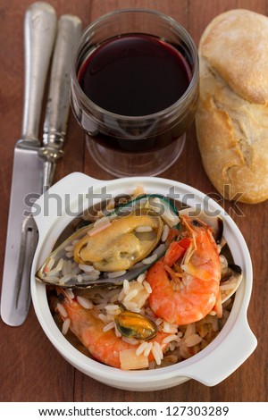 rice with seafood in the bowl with red wine and bread