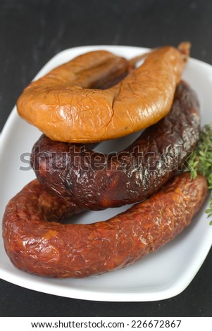 different smoked Portuguese sausages on white dish on black background