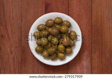 olives in olive oil on white plate on brown background