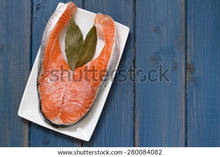 frozen salmon on white dish on blue wooden background
