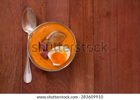 tomato soup with bread, boiled egg in bowl with spoon