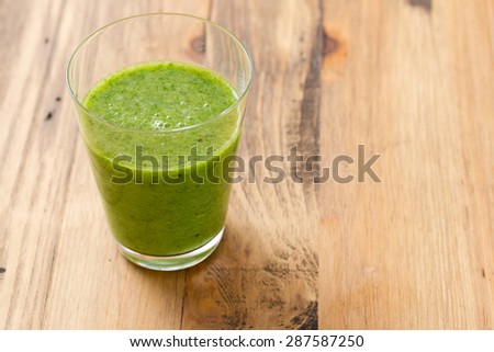 green smoothie in glass on brown wooden background