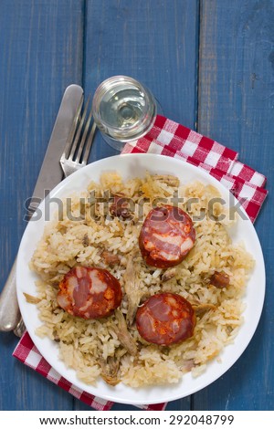 duck rice with sausages on plate and glass of wine
