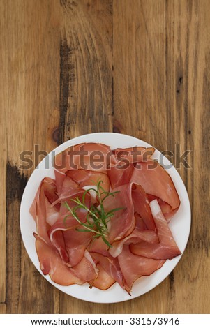 prosciutto on white plate on brown background