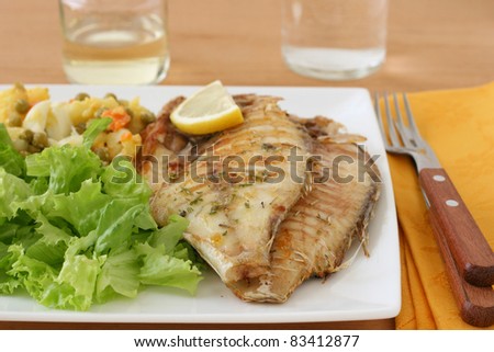 fried fish with salad and wine