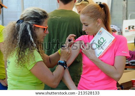 KAROLINKA, CZECH REPUBLIC - AUGUST 08, 2014: Female racer takes her start number at  the Valachia Man triathlon