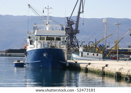 Fishing ship in port with little boat tied behind her