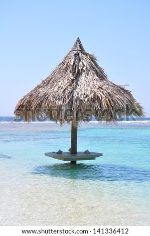 A thatch-covered beach side bar in clear blue waters in Honduras