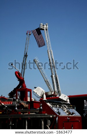 US Flag held up between two firetruck ladders in the sky
