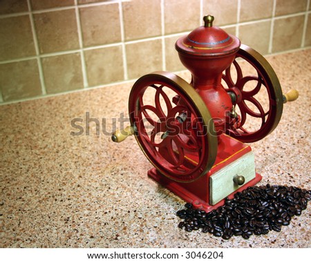 Red Antique Coffee Grinder and Whole Coffee Beans on Granite Kitchen Counter