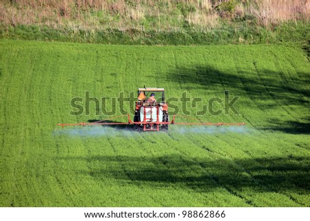 farm tractor spraying field before planting