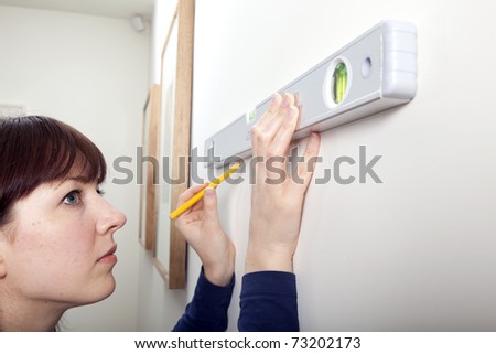 A woman using a spirit level to complete a DIY task.