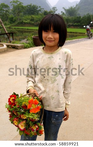 YANGSHUO, CHINA - MAY 14: A girl sells flowers near the river on May 14, 2010 in Yangshuo, China