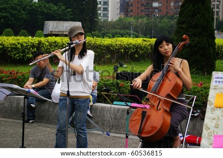 TAIPEI, TAIWAN - MAY 18: Two girls sing along the street for charity purpose on 18 May, 2009 in Taipei. They play different instruments.