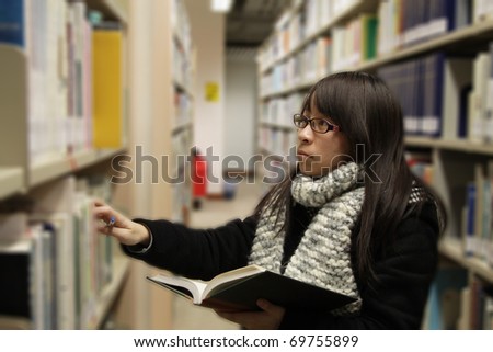 An Asian girl who is finding books in library of a University