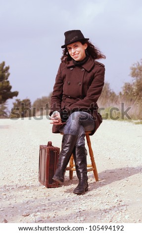 Girl with a suitcase sitting on a stool