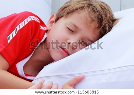 cute 7 years old boy sleeping on white pillow in summer cafe