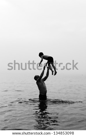 father and son swimming in the sea at sunset