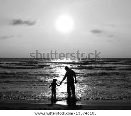 father and son on a walk by the sea at sunset. Black and white photo.